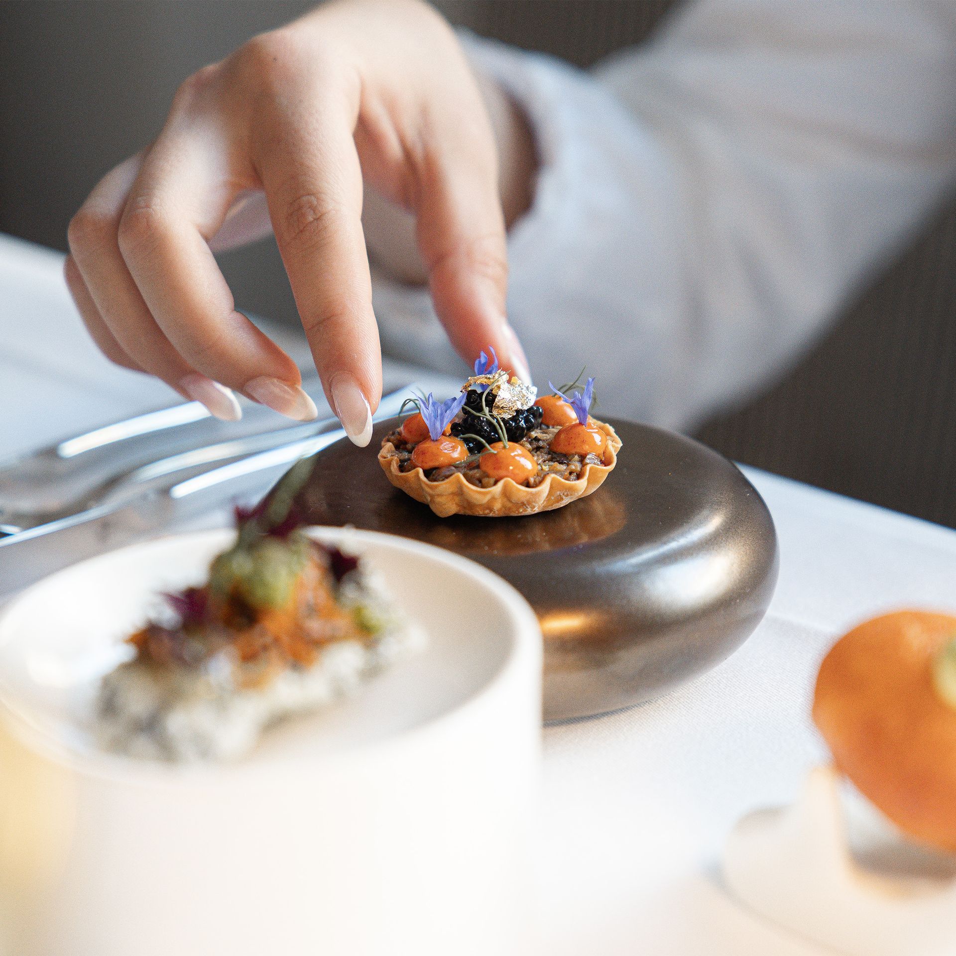 Präzises Service-Detail im Restaurant Sorriso: Petit Four wird auf dunklem Naturstein angerichtet